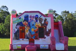 Pink Sesame Street jumping castle with slide